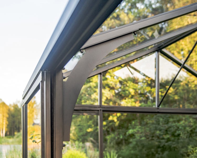 Detailansicht einer Gewächshausecke mit anthrazitfarbenem Aluminiumrahmen und Glaselementen.