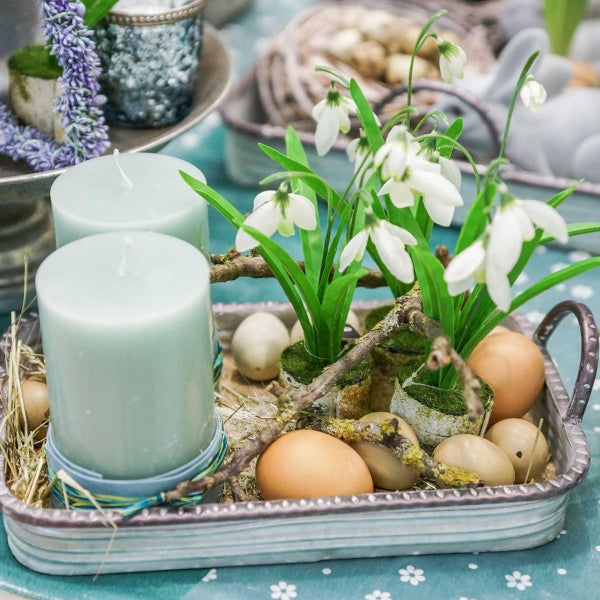 Dekorationstablett mit Kerzen, Eiern und Frühlingsblumen als Tischdekoration