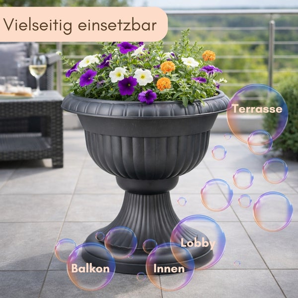 Dunkler Pflanzpokal aus Kunststoff mit weißen Blumen im Garten. Symbol für Langlebigkeit und Hinweis auf Formstabilität und Farbechtheit.