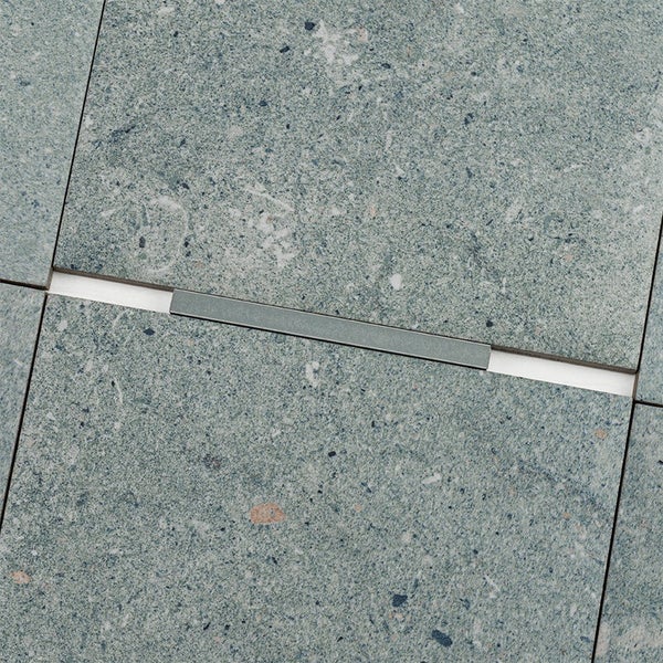 Fliesenbelag aus Natursteinoptik mit einer schmalen, flachen Metalleinlage in der Fuge für ein modernes Bodenbild.