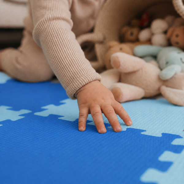 Kind spielt auf einer weichen Puzzlematte aus Schaumstoff mit Kuscheltieren in einem Korb.