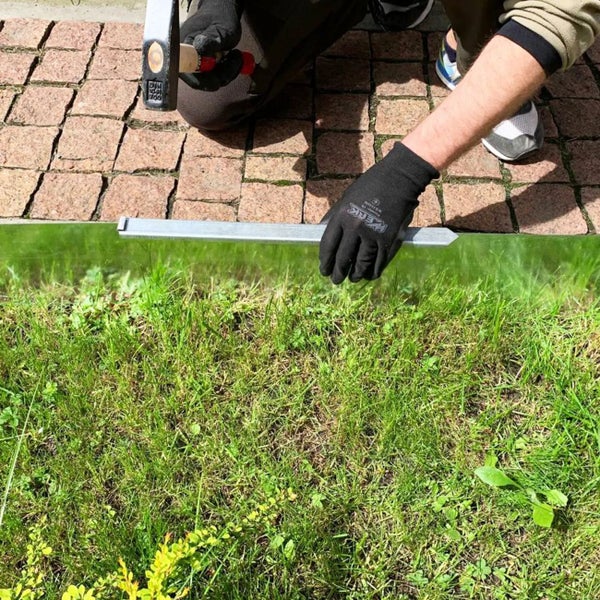 Person installiert Rasenkante mit Hammer