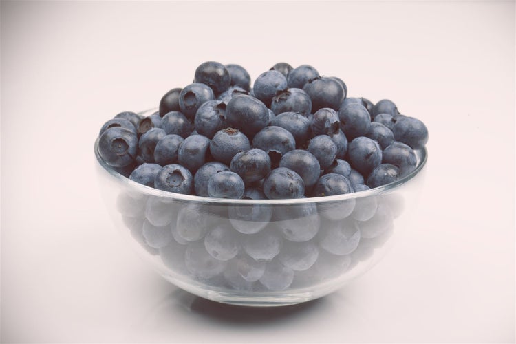Eine gläserne Schale gefüllt mit frischen Heidelbeeren.