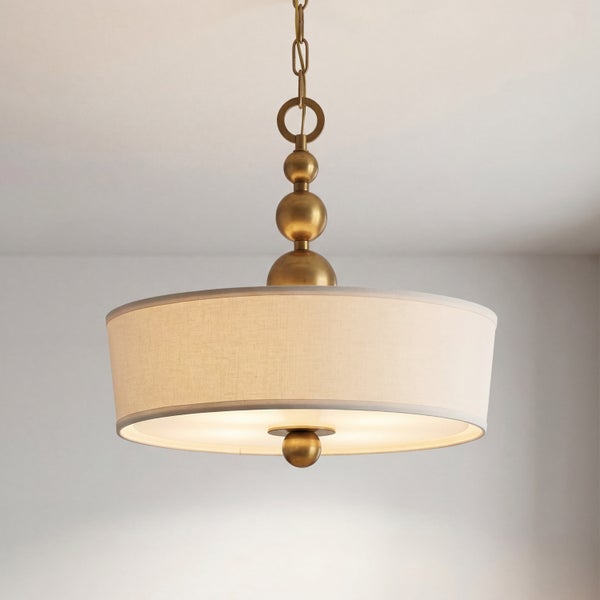 Pendelleuchte mit rundem Stoffschirm in Creme und dekorativen messingfarbenen Metallelementen an der Kette.