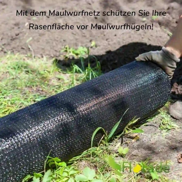 Eine Person verlegt ein engmaschiges Maulwurfnetz auf einem Gartenboden zur Sicherung der Rasenfläche.