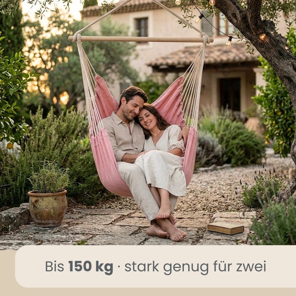 Ein Paar sitzt in einem rosa Hängesessel in einem hellen Garten mit Steinboden und Pflanzen. Belastbar bis 150 Kilogramm.