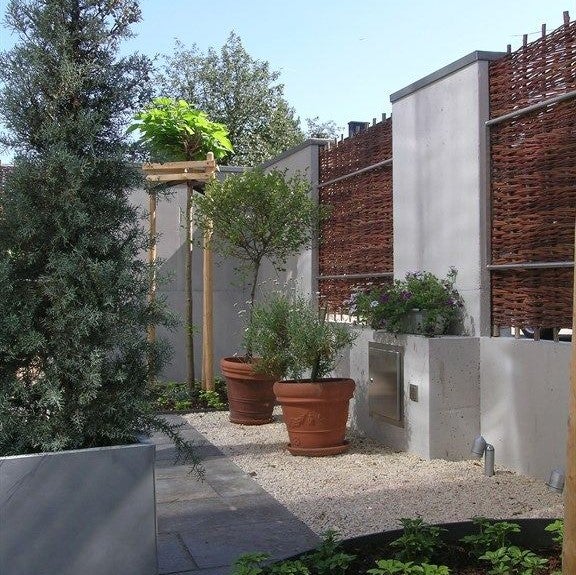 Gestalteter Garten mit Pflanzen, Flechtzaun und Steinelementen