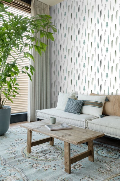 Wohnzimmer mit Feder-Tapete, Sofa, Holztisch und Teppich