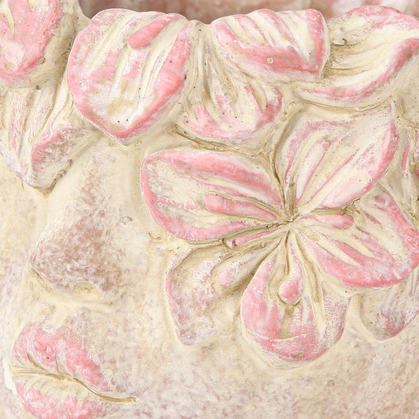 Nahaufnahme eines Pflanzgefäßes in Form eines Gesichts mit dekorativen rosa Blumen in Reliefoptik.