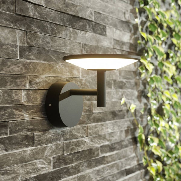 Moderne Außenwandleuchte in Schwarz an einer Natursteinwand, schirmförmiges Design mit warmweißem Licht.