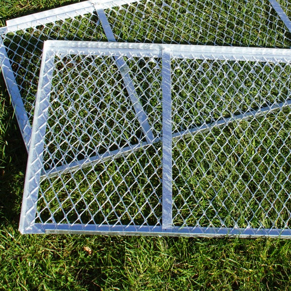 Zwei verzinkte Gitterroste liegen auf Rasen.