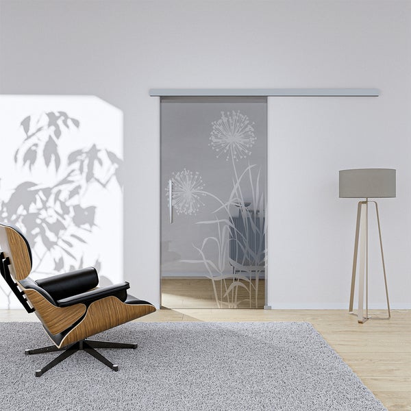 Ganzglasschiebetür mit Pusteblumen-Dekor, Griffstange und Laufschiene in einem hellen Wohnraum mit modernem Sessel.