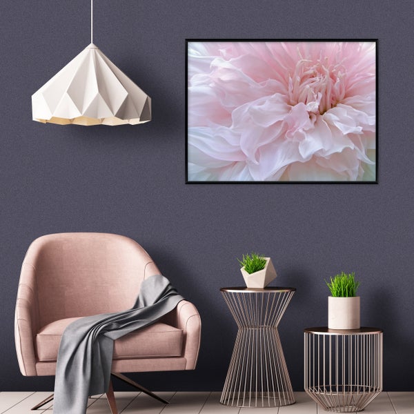 Wohnbereich mit einem Sessel, Beistelltischen, einer Pendelleuchte und einem Wandbild mit einer Blumenblüte.