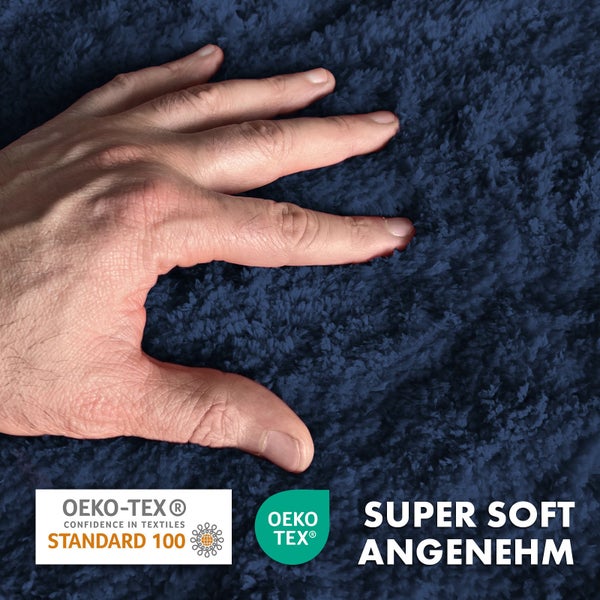 Detailansicht eines blauen, superweichen Teppichs mit Öko-Tex Siegel und einer Hand, die die Oberfläche berührt