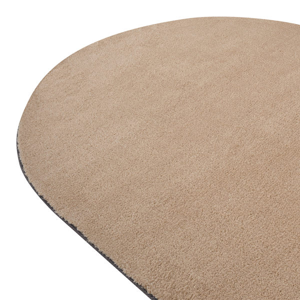 Beigefarbener ovaler Teppich mit weichem Flor und geketteltem Rand.
