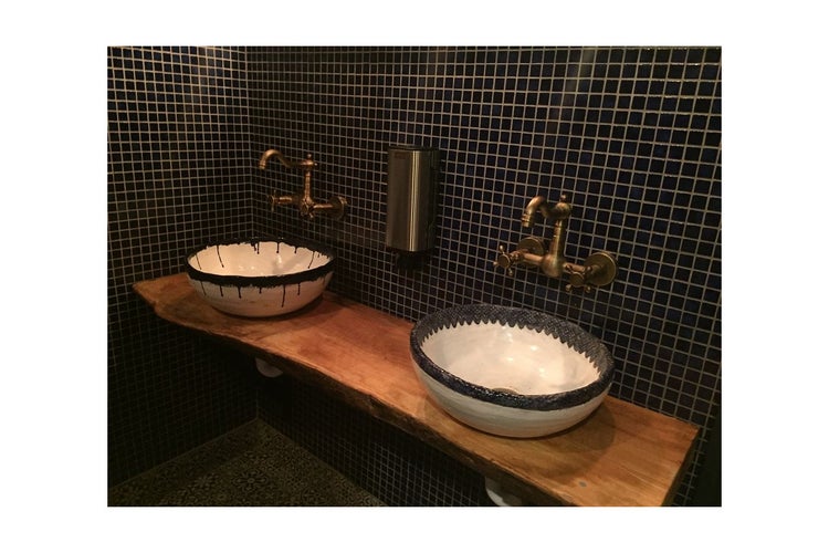 Badezimmer mit zwei Waschbecken auf Holzplatte und Armaturen