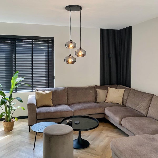 Wohnzimmer mit Ecksofa, Couchtisch und Hängeleuchte mit drei Glaskugeln