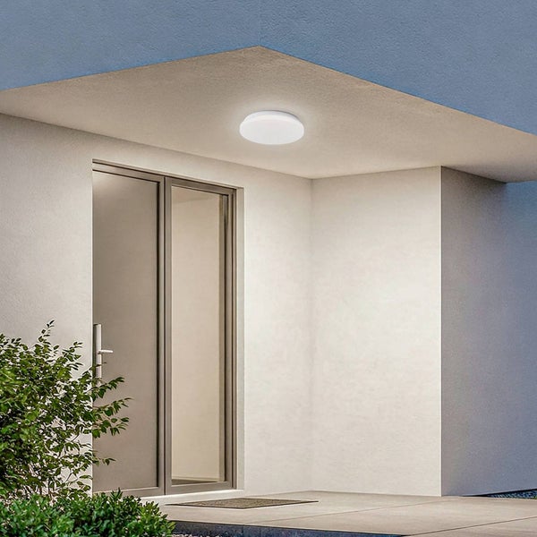 Runde LED-Außen-Deckenleuchte flach montiert im überdachten Eingangsbereich neben einer Glastür.
