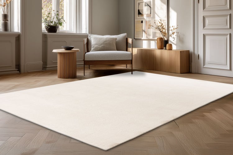 Heller Wohnzimmerteppich in einem modernen Wohnraum mit Parkettboden, Sessel und Holzmöbeln.