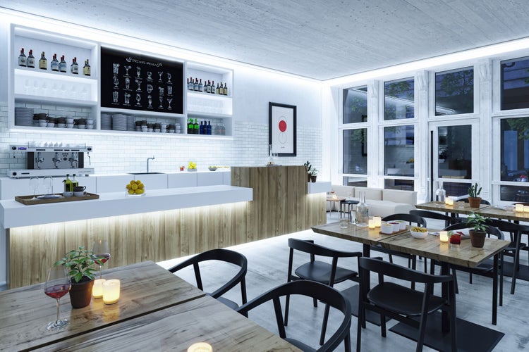 Helle, moderne Café-Einrichtung mit weißem und hölzernem Tresen, Holztischen, schwarzen Stühlen und großen Fenstern in organisierter Atmosphäre.