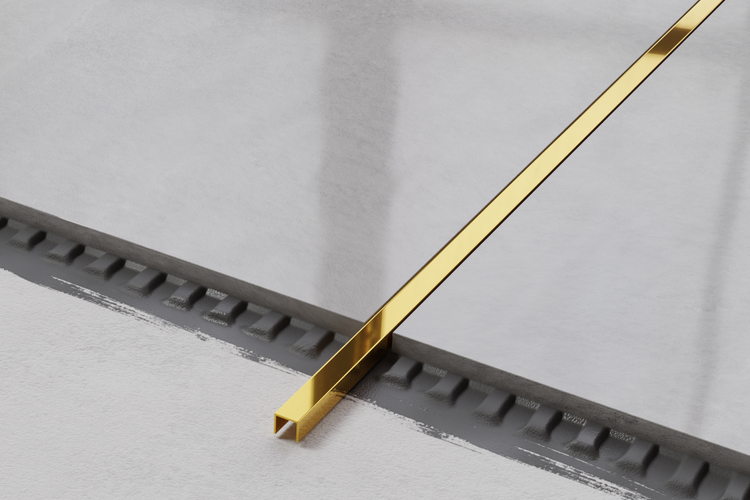 Goldfarbene Fliesenschiene auf hellem Untergrund