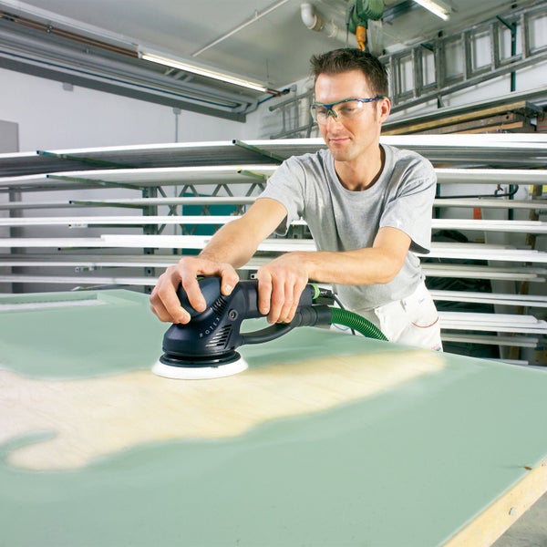 Mann schleift Oberfläche mit Exzenterschleifer