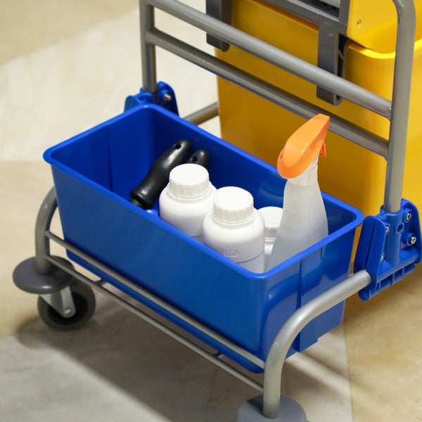 Reinigungswagen mit Ablagekorb, gefüllt mit verschiedenen Reinigungsmitteln in Flaschen und einer Sprühflasche für professionelle Reinigungsarbeiten.
