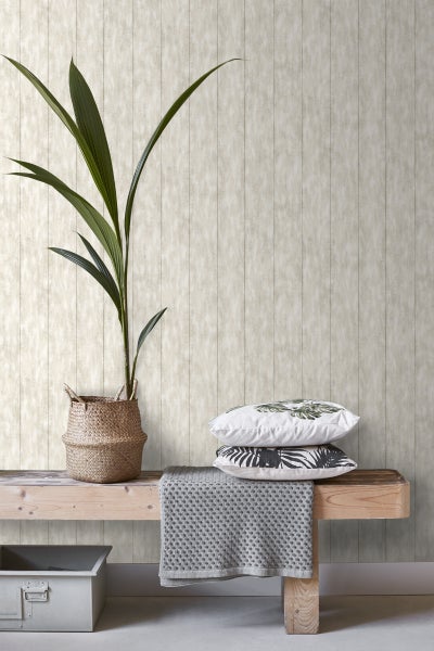 Dekorative Szene mit Holzbank, Zimmerpflanze und Kissen vor einer Wandtapete
