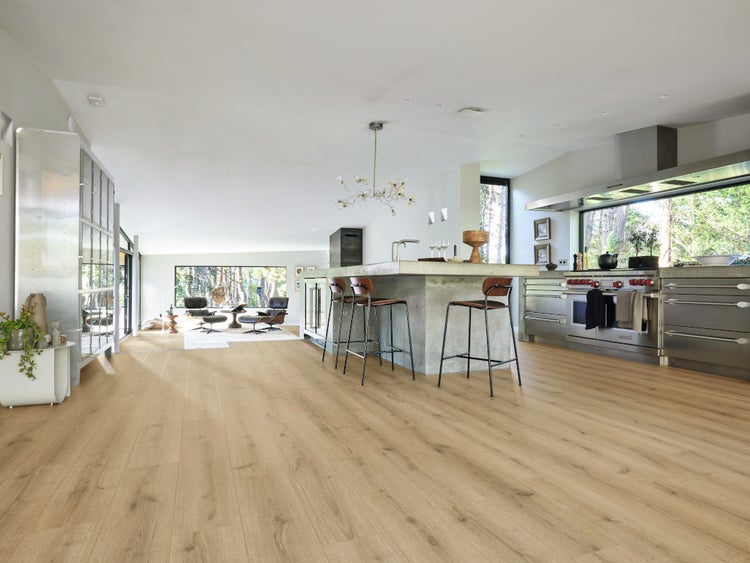 Offene moderne Wohnküche mit Laminatboden in Holzoptik, Kücheninsel mit Barhockern und großen Fensterfronten mit Blick ins Grüne.