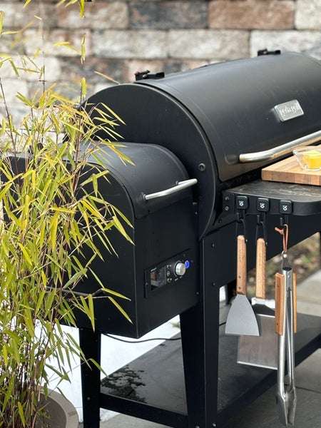 Schwarzer Pelletgrill mit Grillbesteck und Bambuspflanze