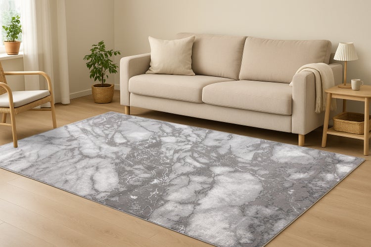 Wohnzimmer mit einem großen Teppich in Marmoroptik vor einem Sofa, mit Holzboden, Pflanzen und Beistelltisch.