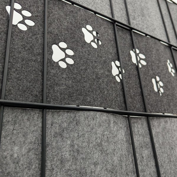 Detailansicht eines Hundezwingers mit grauer Filzverkleidung und weißen Pfotenabdrücken
