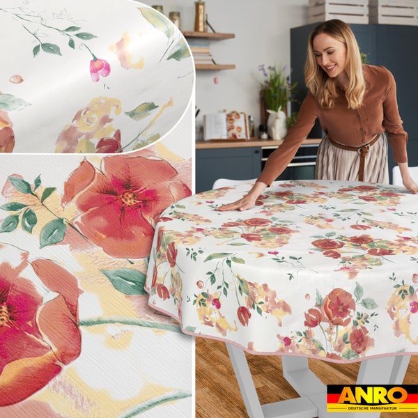 Frau glättet eine runde Tischdecke mit Blumenmuster in einer hellen Küche, Detailansicht der abwischbaren Oberfläche. ANRO Logo.