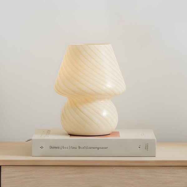 Tischleuchte im Pilzdesign mit gewirbelter Textur, auf einem Buch platziert