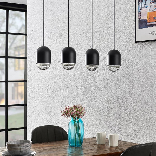 Vierflammige Pendelleuchte mit Leuchtmitteln mit eingeschlossenen Luftblasen über einem Holztisch.