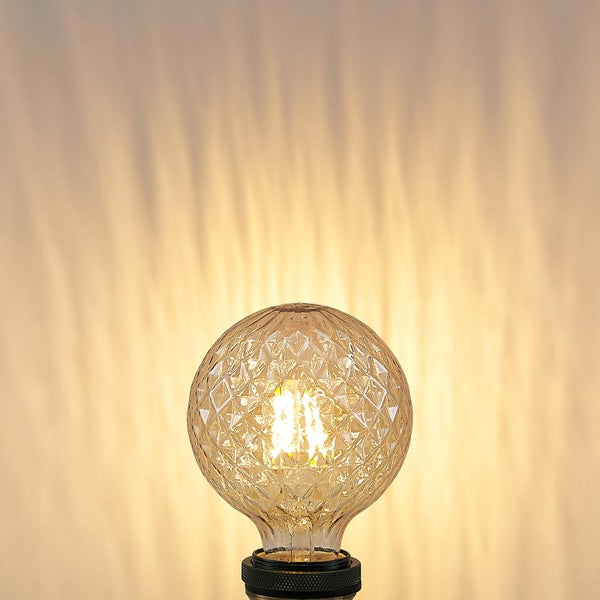 LED-Filament-Leuchtmittel in Globform mit rautenförmig strukturiertem Glas und warmweißem Licht.