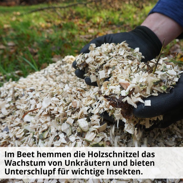 Holzhackschnitzel werden von Händen mit Gartenhandschuhen gehalten