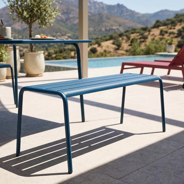 Moderne Gartenbank aus Metall in Blau auf einer sonnigen Terrasse mit Pool und Bergblick.
