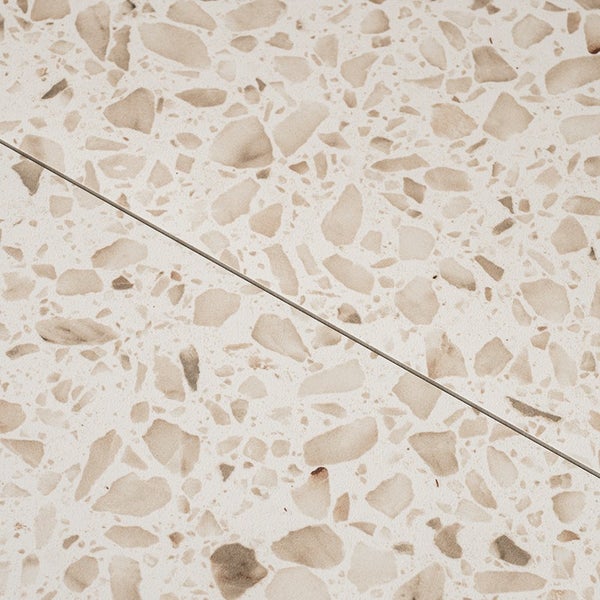 Fliese in Terrazzo Optik mit eingebetteten Gesteinspartikeln und einer sichtbaren Fuge