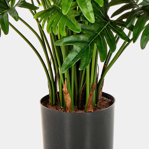 Künstliche Philodendron-Pflanze mit großen grünen Blättern in einem schwarzen Topf.