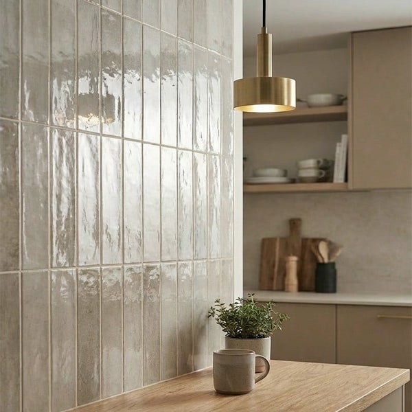 Moderne Kueche mit vertikal verlegten, glänzenden Wandfliesen im Stäbchenformat und einer hängenden Pendelleuchte über einer Holztheke.