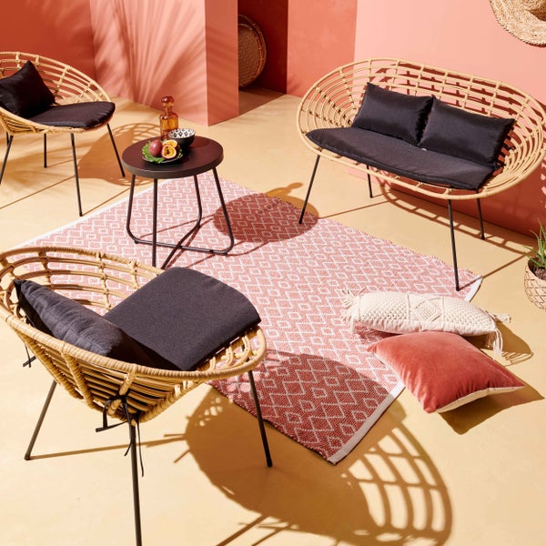 Garten-Lounge-Set bestehend aus zwei Sesseln und einer Bank mit schwarzen Polstern sowie einem runden Beistelltisch auf einem Außenteppich.