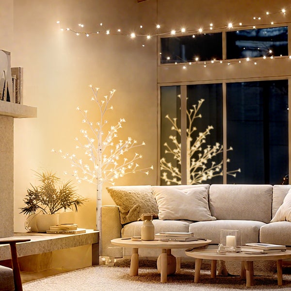 Wohnzimmer mit beleuchteter Dekoration inklusive Baum und Lichterkette