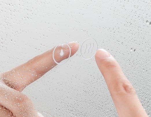 Finger berührt Touch-Sensor für Beleuchtung und Spiegelheizung auf einem beschlagenen Badspiegel.