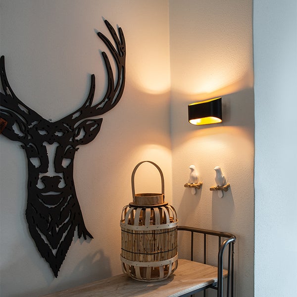 Dekorative Szene mit Geweih, Wandleuchte und Windlicht auf einem Tisch