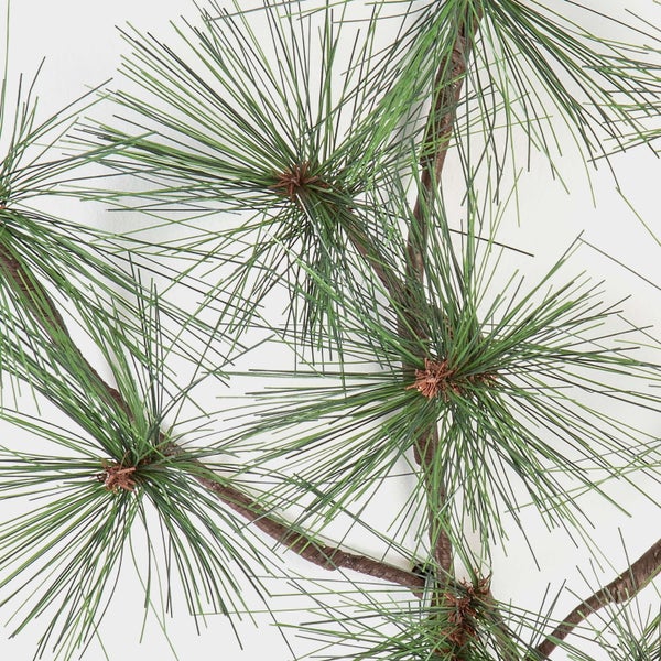 Künstliche Bambuspflanze mit dichten grünen Blättern und mehreren braunen Stämmen in einem schwarzen Topf.