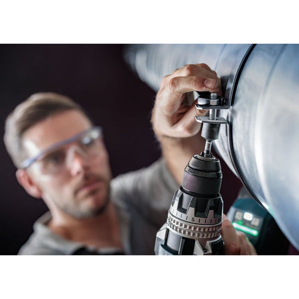 Ein Mann befestigt mit einem Akkuschrauber eine Rohrschelle an einem Rohr.