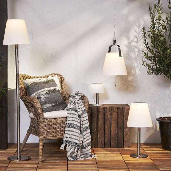 Terrasse mit Rattan Sessel, Kissen, Decke, Stehlampe, Pendelleuchte und Tischlampen.