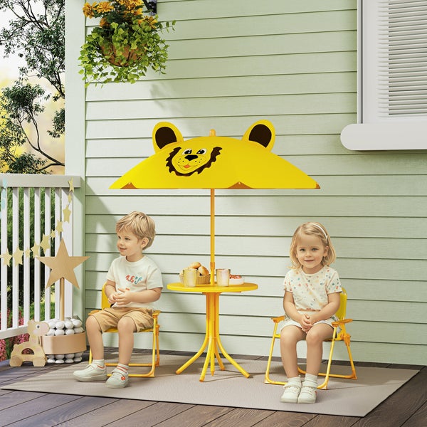 Kinder sitzen an einem gelben Gartentisch mit Sonnenschirm in Löwenform.