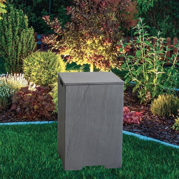 Gartenhocker in Basaltoptik in einem bepflanzten Garten auf einer Rasenfläche.
